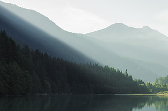 Misty Mountain Lake with Sunbeams and Forest Reflection
