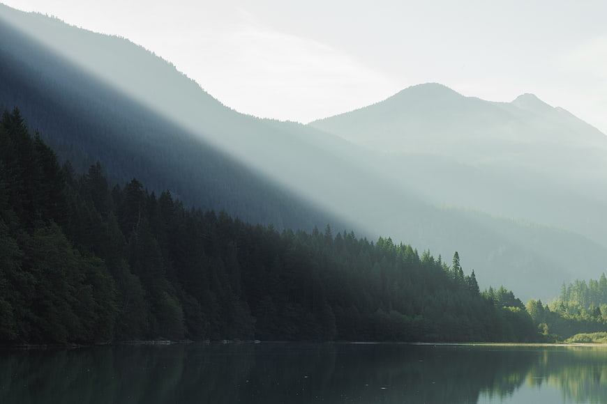 Misty Mountain Lake with Sunbeams and Forest Reflection