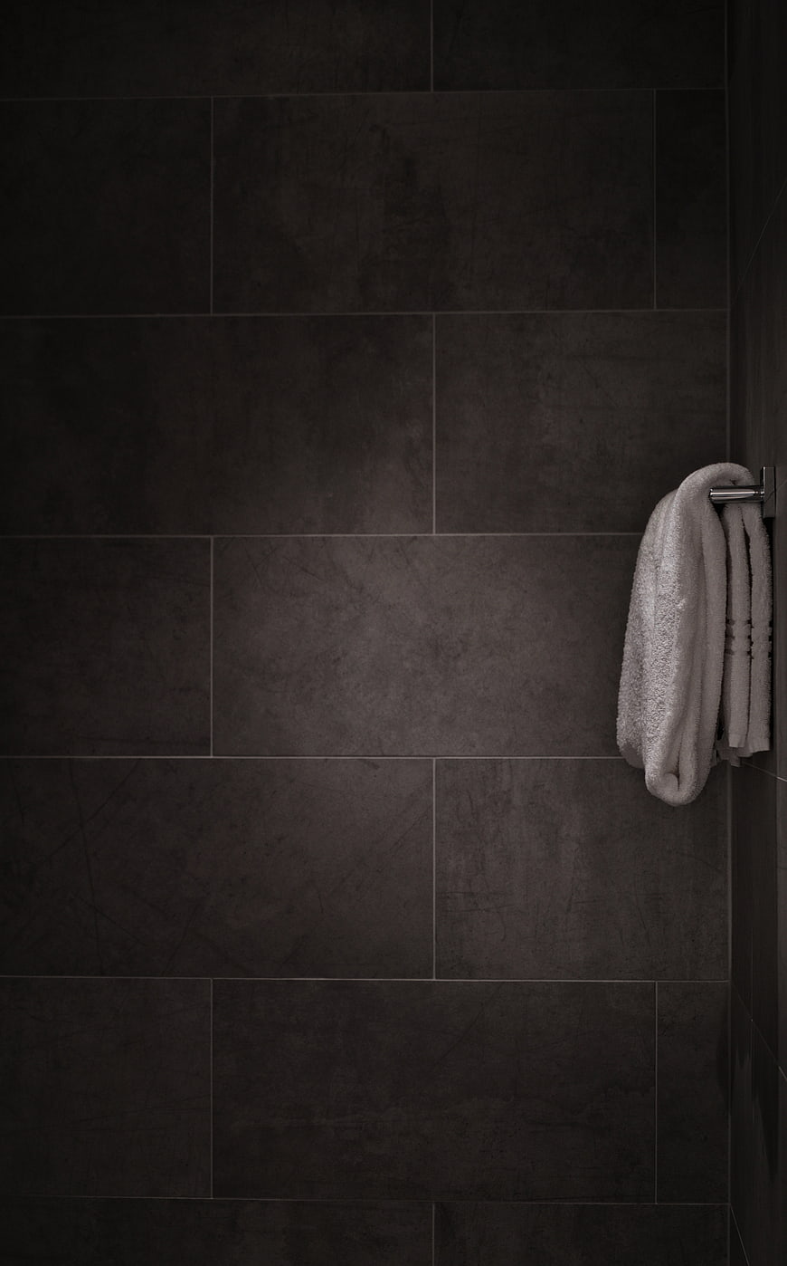 Dark Gray Tiled Bathroom Wall with White Towel