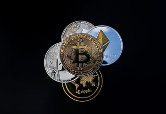 Stack of physical cryptocurrency coins including Bitcoin, Ethereum, Litecoin, and Ripple on black background