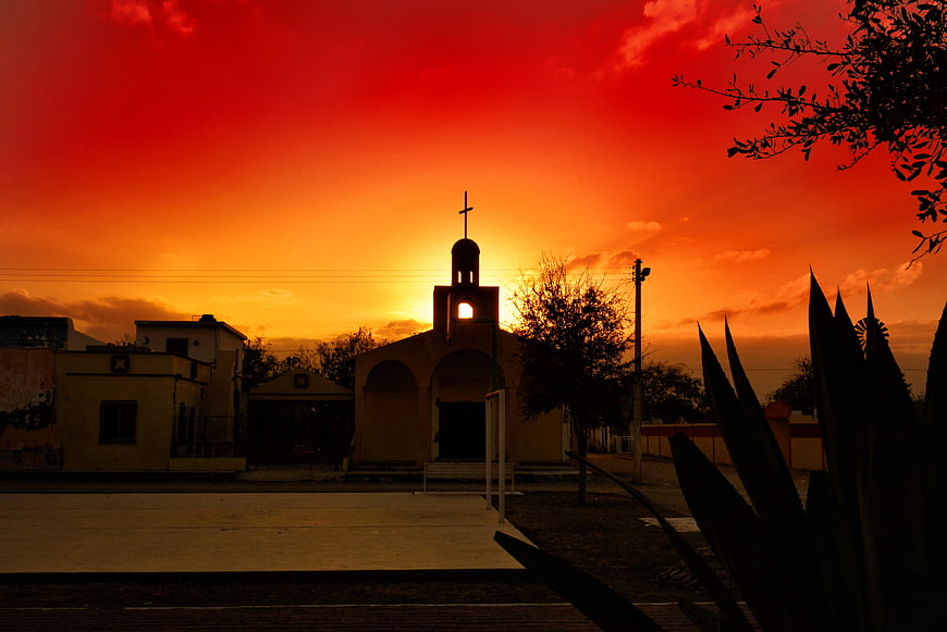 Silhouette of Church Tower Against Vibrant Orange Sunset Sky