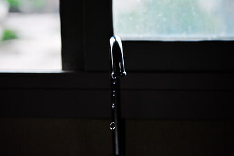 Dripping faucet with water drops against dark background