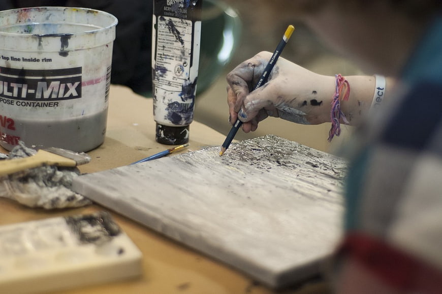 Close-up of artist hand painting with pencil and acrylics