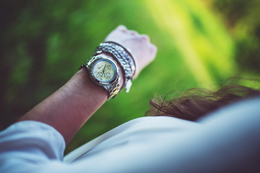 Woman checking silver watch on wrist outdoors
