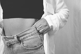 Woman holding out oversized jeans waist to show weight loss