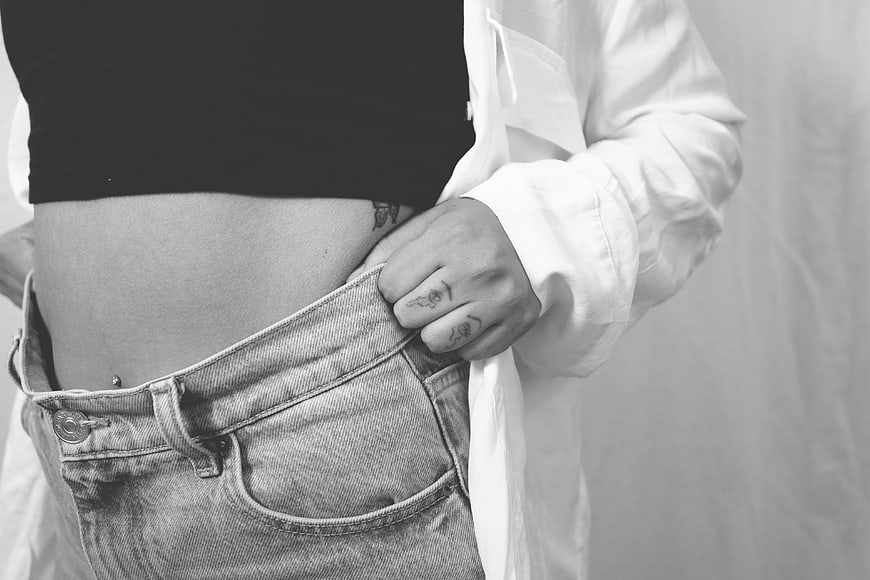 Woman holding out oversized jeans waist to show weight loss