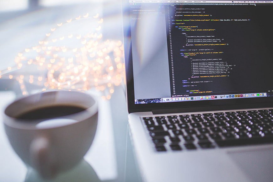 Laptop with Code and Coffee Cup on Desk