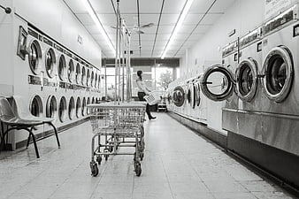 Black and white woman doing laundry in self-service shop