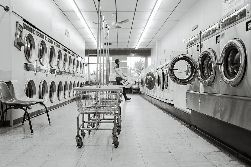 Black and white woman doing laundry in self-service shop