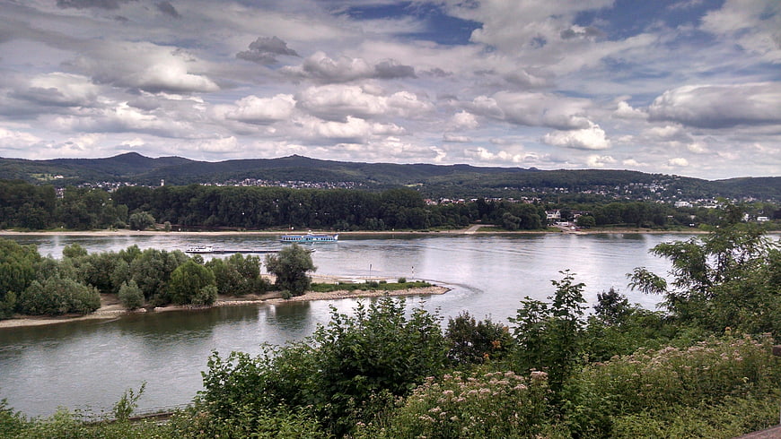 Wide river landscape with boats and distant hills under cloudy sky