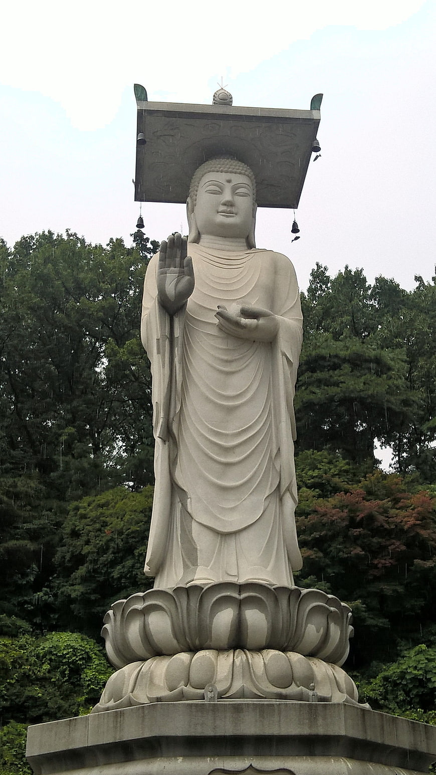 White Buddha Statue on Lotus Pedestal in Rain