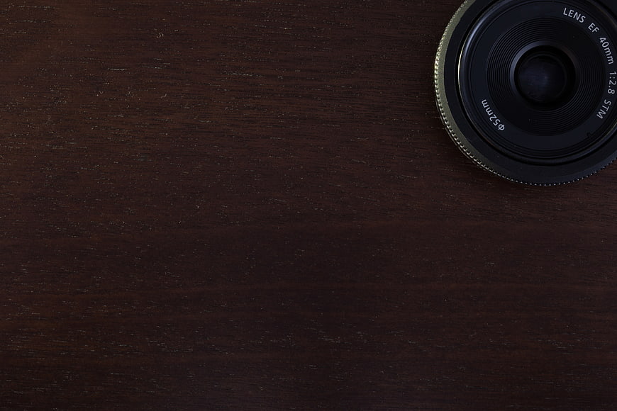 Camera Lens on Dark Wood Desk Background
