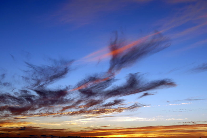 Dramatic Sunset Sky with Streaked Clouds and Golden Horizon