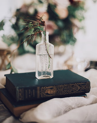 Vintage glass bottle with dried flowers on antique books