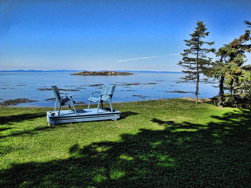Blue Adirondack Chairs on Grassy Lawn Overlooking Ocean