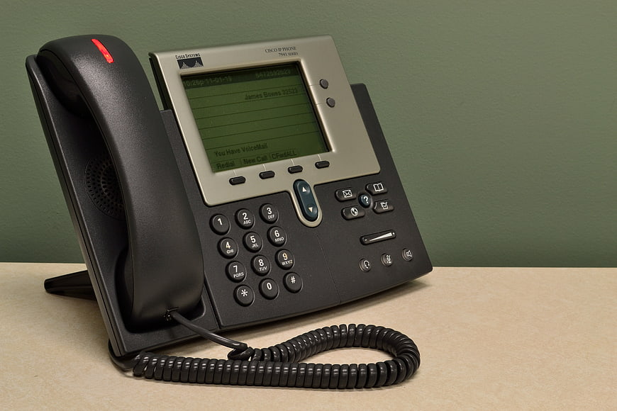 Cisco IP Phone on Office Desk with Green Background