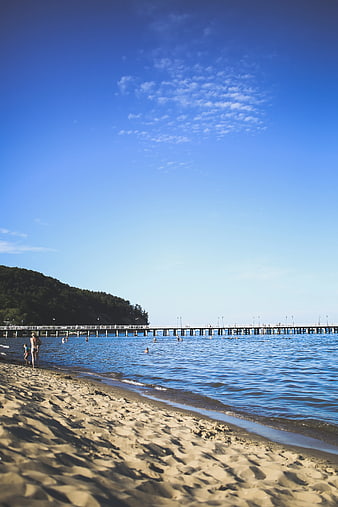 Sunny Beach with Long Pier and Blue Sky