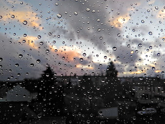 Raindrops on window glass with blurred cityscape background