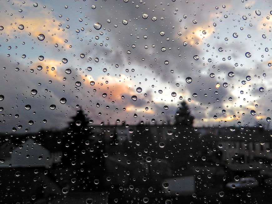 Raindrops on window glass with blurred cityscape background