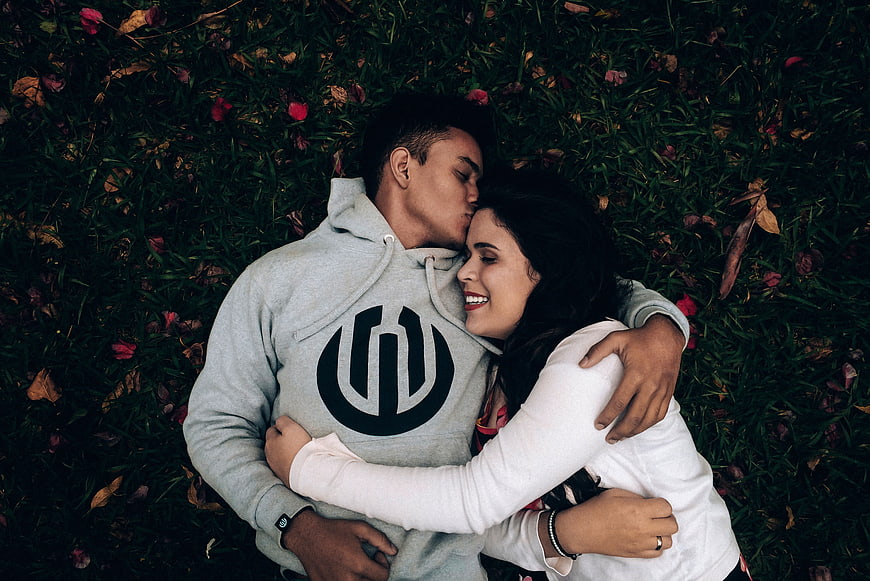 Happy couple hugging and kissing while lying on grass