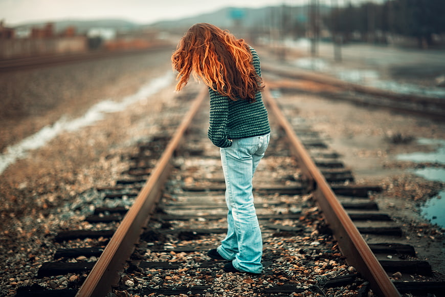 Woman with red hair standing alone on railway tracks