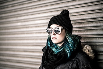 Woman with blue hair and sunglasses against metal shutter