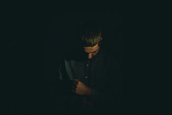 Sad man looking down in dark room