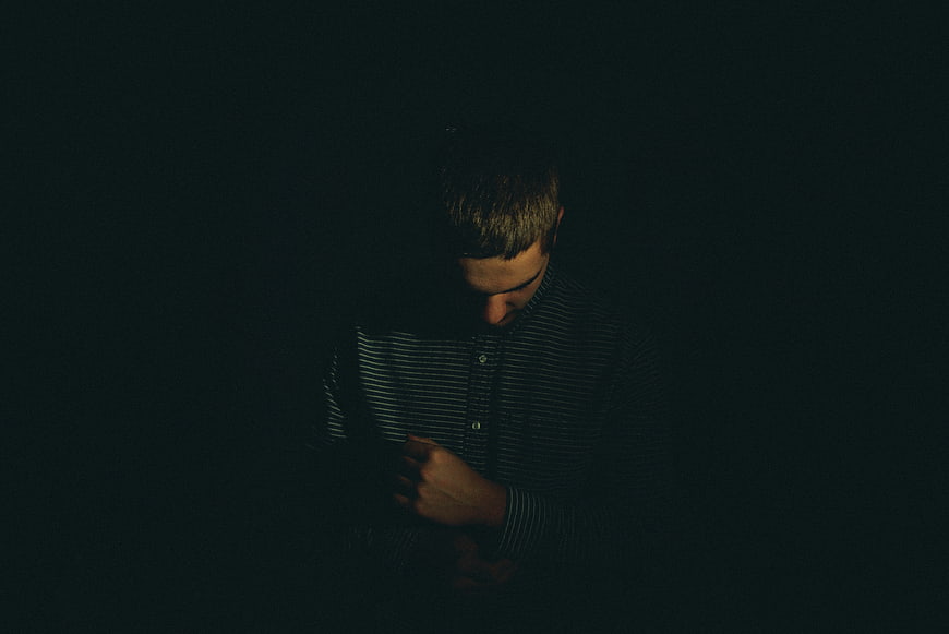 Sad man looking down in dark room