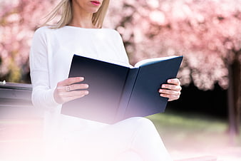 Woman Reading Book Outdoors Under Pink Blossoms