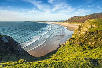 Scenic coastal landscape with sandy beach and green cliffs