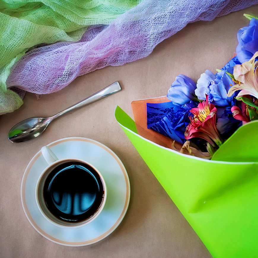 Flat lay of coffee cup and colorful spring flower bouquet