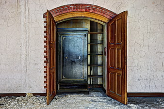 Old Safe Behind Open Wooden Doors in Cracked Wall