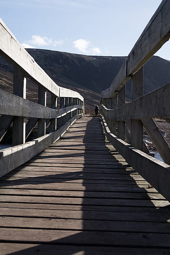 Wooden Bridge Leading to Mountain Landscape with Lone Walker