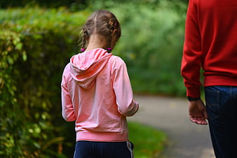 Child and adult walking side by side on a park path