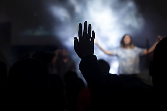 Silhouette of hand raised in worship at concert