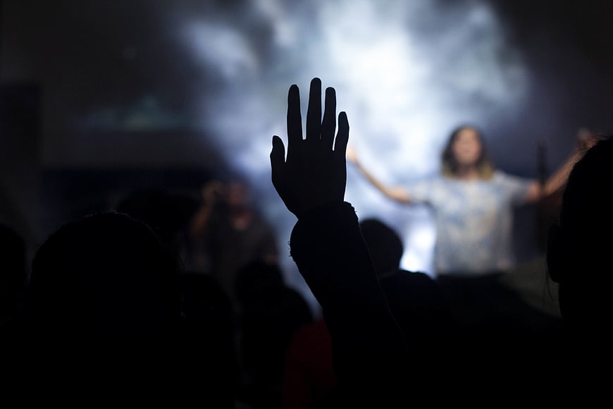 Silhouette of hand raised in worship at concert