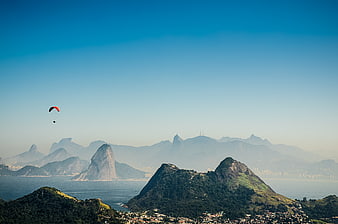 Paraglider flying over Rio de Janeiro mountains and Sugarloaf Mountain