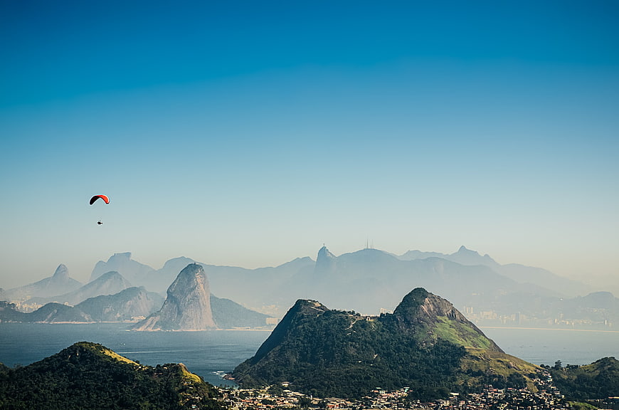 Paraglider flying over Rio de Janeiro mountains and Sugarloaf Mountain