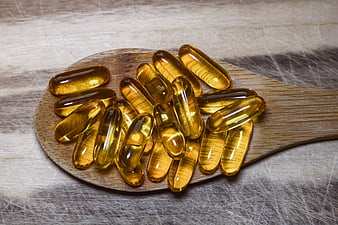 Golden Fish Oil Capsules on Wooden Spoon