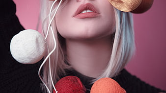 Close-up of woman with colorful textured balls and pink background
