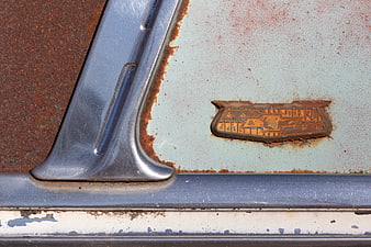 Close-up of Rusty Vintage Chevrolet Emblem on Weathered Car Body