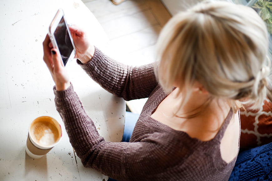 Overhead view of woman using smartphone with coffee