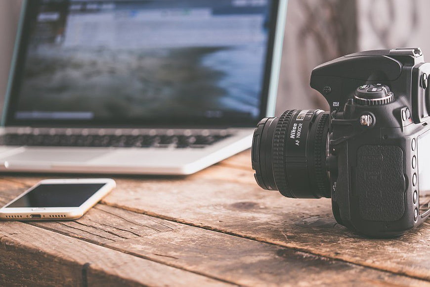 DSLR Camera, Smartphone, and Laptop on Rustic Wooden Desk
