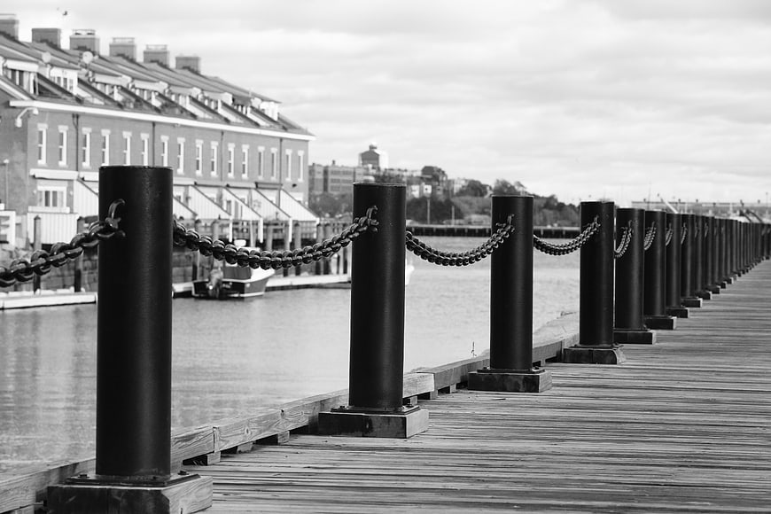 Black and white wooden pier with black posts and chains