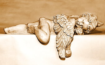 Sepia-toned sleeping cherub statue lying on ledge