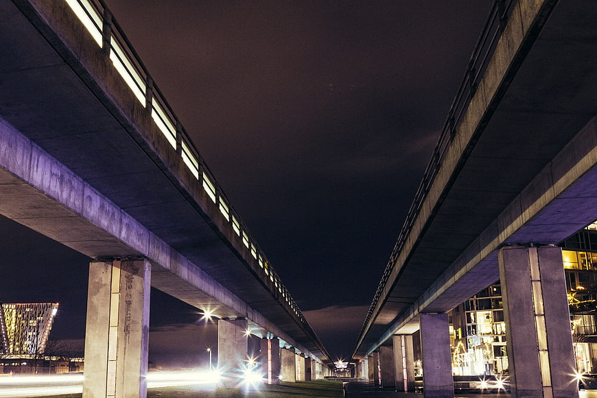 Night view of dual concrete highway overpasses with city lights