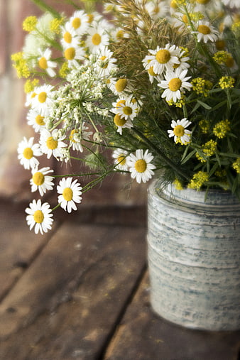 Rustic bouquet of white daisies and yellow wildflowers in a ceramic vase
