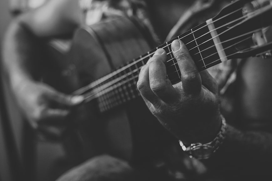 Close-up of hands playing acoustic guitar in black and white