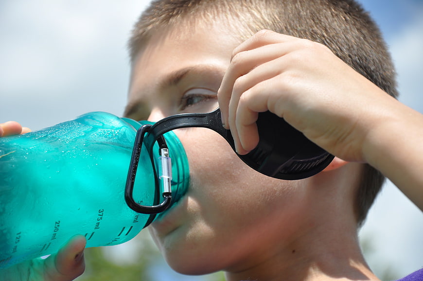 Close-up of Boy Drinking Water from Blue Bottle