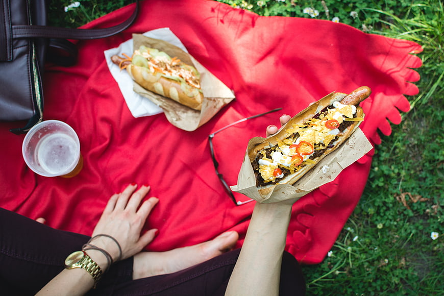 Top view of gourmet hot dogs on a red picnic blanket
